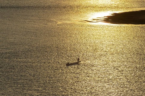 Fisherman with longtail boat (Thai: Ruea Hang Yao) at sunrise, Mekong between Thailand and Laos