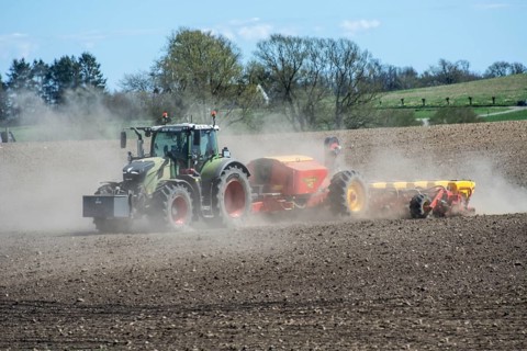Farming, sowing with tractor in springtime in dusty arable field in Ystad municipality, Skåne