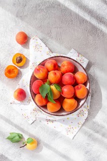 Fresh apricots in a bowl, on a bright table, natural light, top view, no people