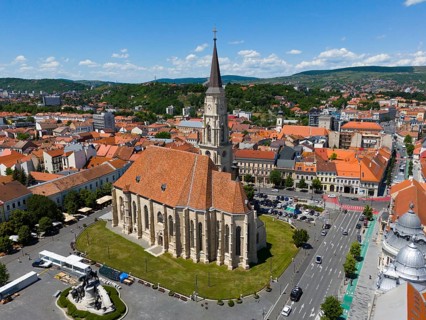 Large historic church in the city center with surrounding buildings and mountains in the