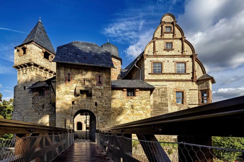 An impressive castle with a wooden bridge characterized by stone walls and towers, The Upper Castle