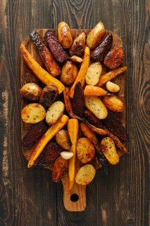 Vegetables placed on wooden board show variety of colors and shapes. Potatoes, carrots and beets