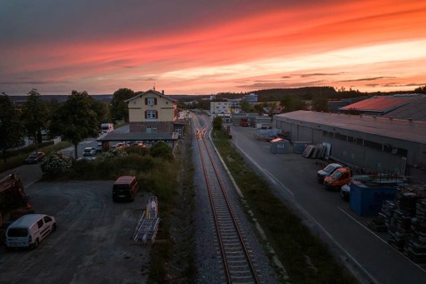 Industrial area at sunset with tracks, sky colored in warm shades ranging from orange to purple,