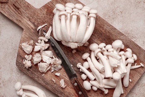 Freshly sliced Shimizhi mushrooms, on a wooden chopping board, ready to cook, close-up, no people