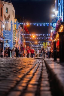 A busy cobblestone street with people and colorful lights at night, nightlife, Dublin, Ireland