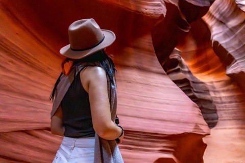 Woman wearing a hat admiring the unique geological formations and vibrant colors inside the slot