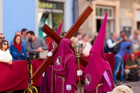 Masked participants in purple costumes wear crosses during a procession, Good Friday procession,