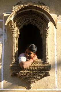 Young woman looking out of a decorated window, Jaisalmer, Rajastan, India