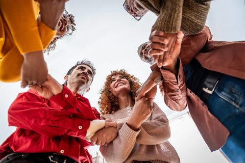 Diverse adults in a support circle holding hands, symbolizing unity, empathy and teamwork in a