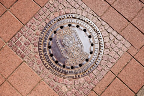 Manhole cover, city coat of arms, city of Kevelaer, footpath made of concrete paving stones and