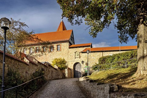 Old building with red roof and massive brick walls along a paved path, The Lower Castle of