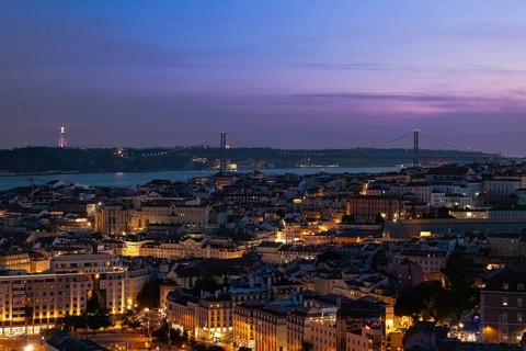 High angle panoramic view of Lisbon city skyline at dusk with illuminated streets, historic