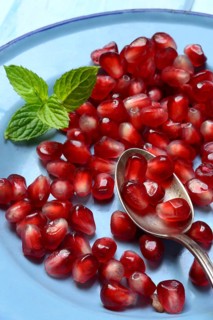 Pomegranate seeds and spoons on plate, Punica granatum