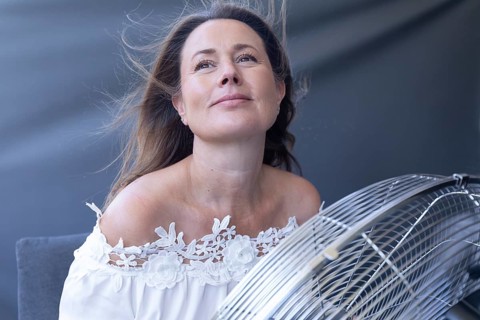 Woman enjoying cool airflow from a fan in a bright indoor portrait. during hot weather at home