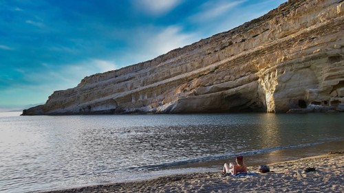 Neolithic caves, former hippie paradise, rocky coast with calm sea and blue sky, two people on the