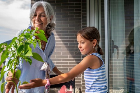 Grandmother and granddaughter share a joyful moment, bonding while planting a young pepper plant