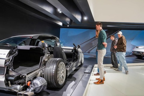 Visitors look at a partially dismantled car in the museum exhibition room, Porsche Museum,