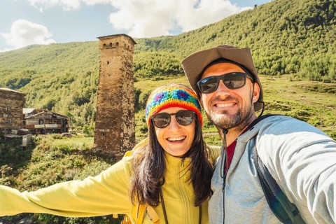 Smiling happy caucasian couple taking selfie by Ushguli svan tower settlement. Hiking in Svaneti