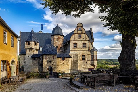 Picturesque view of an old castle with visible towers and a paved road in the foreground, The Upper