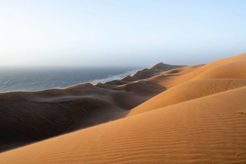 Sand dunes and sea in evening light, impressive desert landscape at sunset, sandy desert, Sandwich
