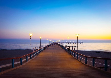 Illuminated romantic vintage Palanga pier after sunset with people walking in beautiful summer