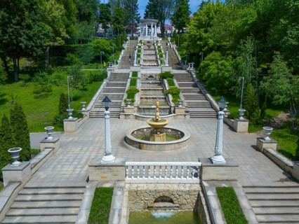 Impressive garden with stairs and fountain in classic style surrounded by lush greenery, cascade