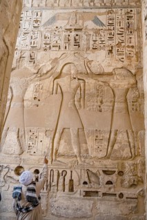 A tour guide points out details of reliefs and hieroglyphs inside Medinat Habu, the ancient