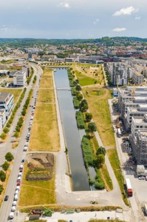 A water channel with surrounding urban development and green spaces from a bird's eye view,