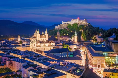 Close-up aerial view of the lit-up Hohensalzburg Fortress and the Salzburg Cathedral during the