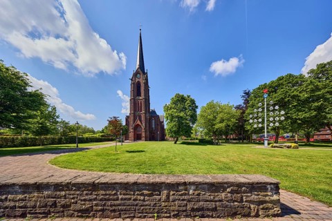 St. Nikolaus parish church, church tower, sandstone wall, green area Bürgerpark, lawn, path, trees,