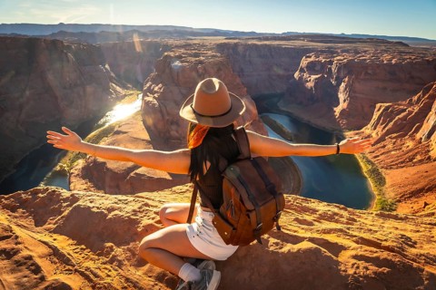 Woman feeling freedom while sitting overlooking the iconic horseshoe bend, a meander of the