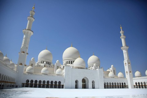 White mosque with several large domes and tall minarets against a clear sky, Sheik Zayed Mosque,