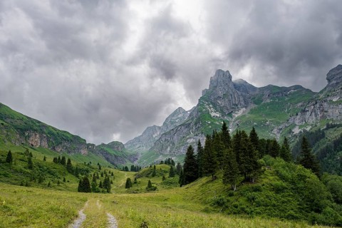Hiking trail in a valley, rocky peak Spaltenhorn, mountain landscape with dark clouds, Bernese
