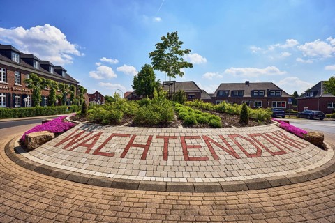 Roundabout, colored concrete paving stones, Wachtendonk lettering, flower bed, tree, road, asphalt,