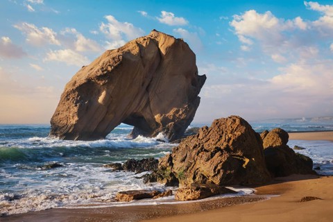 Penedo do Guincho stands majestically at Praia da Santa Cruz as ocean waves crash against the sandy