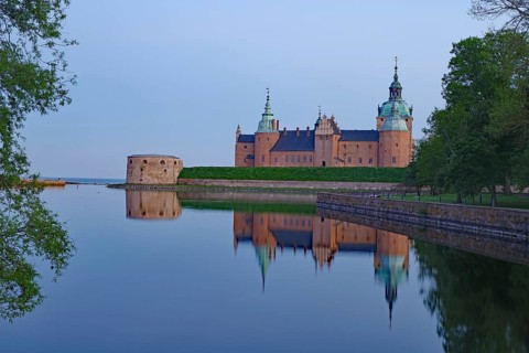 A castle with calm water at dusk, surrounded by lush green spaces and nature, Kalmar Slott, Kalmar,