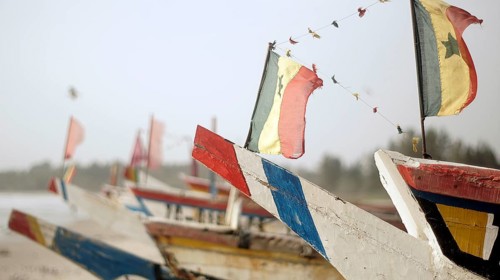 Set of colorful fishing boats with flags, flags of Senegal, on the coast, atmospherically festive,