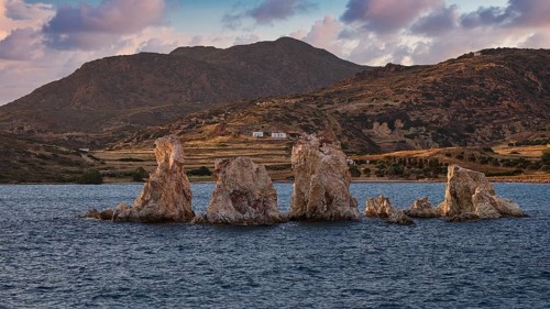Rocks and blue waters with mountains in the background and clouds, Aspragremna, White Cliffs,