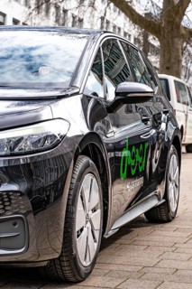Black Volkswagen car with logo on sidewalk in urban area, Deer, E-Carsharing, Stuttgart, Germany