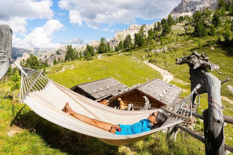 Female hiker resting in hammock at mountain hut on Tre Cime trail in Dolomites enjoying alpine