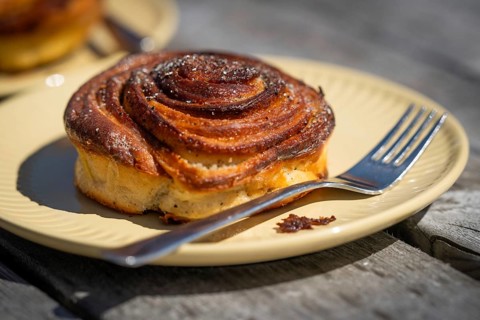 Cinnamon roll and fork lie on a light yellow plate, Houvig, Ringkøbing Fjord, Denmark