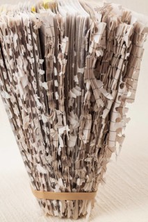 Paper sculpture of loose torn and shredded pages from spiral bound paper note pad held upright