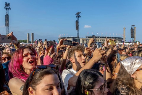Festival visitors with smartphones in front of the Olympic Stadium at the Lollapalooza Festival on