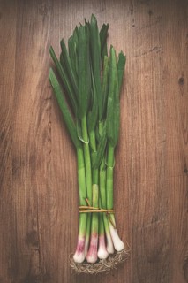 A bunch of young, green garlic, on a wooden table, top view, no people