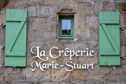 Close-up of an old Breton stone house made of grey granite with distinctive, open wooden shutters