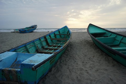 Three boats lie on the beach as the setting sun sets the scene, Ecuador