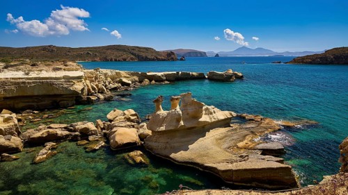 Coastal scene with unique rock formations and crystal clear water under a bright blue sky,