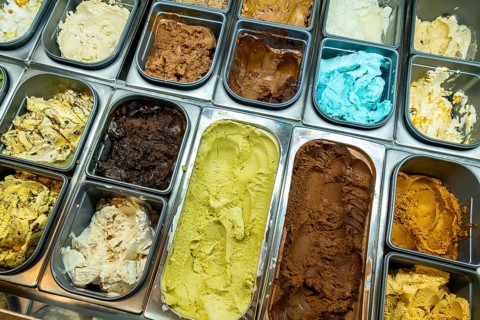 Gelato shop display case presenting a variety of colorful ice cream flavors, including pistachio,