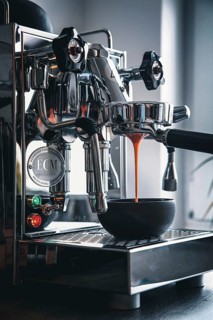 Professional preparation of espresso with a portafilter machine: The espresso flows from the