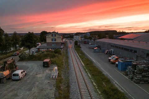 Industrial environment with parking lots and tracks under a spectacular orange sky at sunset,